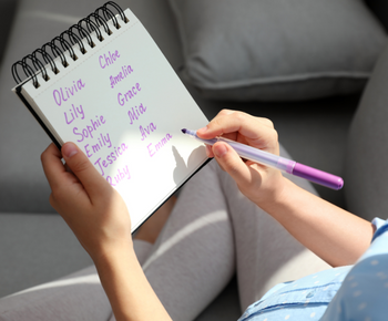 image of women with note pad and is writing baby names down